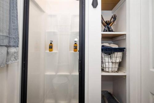 a closet with a glass door with two bottles in it at Experience Tiny Living, in Cape Charles, Va in Cape Charles