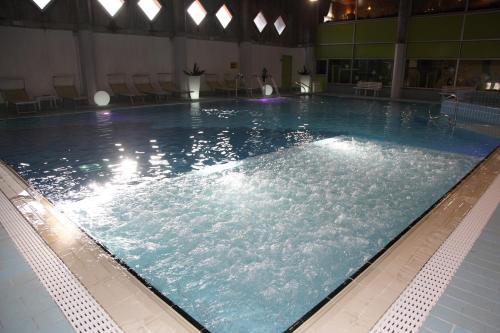 a large swimming pool with blue water in a building at Hotel Nigritella in Selva di Cadore
