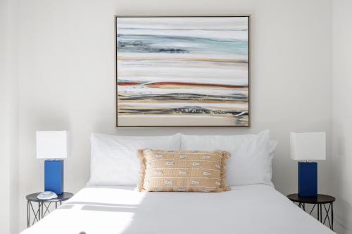 a bedroom with a white bed with a painting above it at Kasa Magnificent Mile Chicago in Chicago