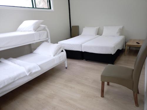 T's Resort & Motel في ميناء ماكواري: غرفة بها ثلاثة أسرة بطابقين وكرسي