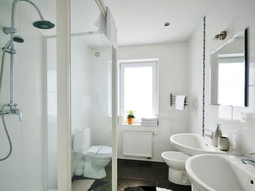 a white bathroom with two sinks and a toilet at Comfortable apartment with a balcony, very close to the sea, Ustronie Morskie in Ustronie Morskie