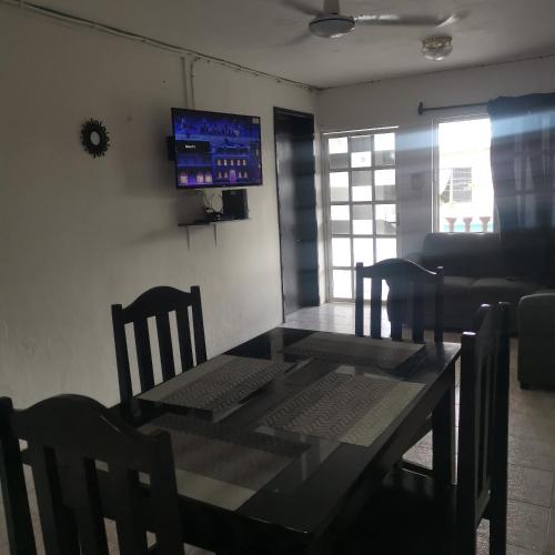 une salle à manger avec une table, des chaises et une télévision dans l'établissement Casa marthita, à Cozumel