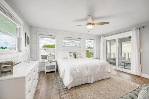 a white bedroom with a bed and windows at Found Your Sol Mate Gorgeous Home w Pool Spa Steps to Bean Point Dogs OK in Anna Maria