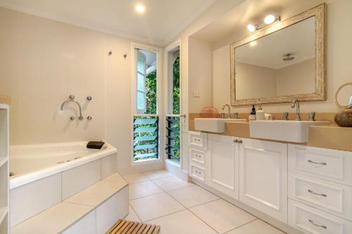 ein Badezimmer mit einer Badewanne, einem Waschbecken und einem Spiegel in der Unterkunft Malawi House in Edge Hill