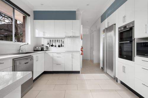 a kitchen with white cabinets and a large window at "Uralla" Lovely house with pool in Bathurst