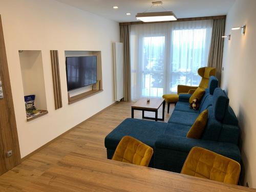 a living room with a blue couch and a television at Wellness & Spa Apartments Lipno - Frymburk in Frymburk