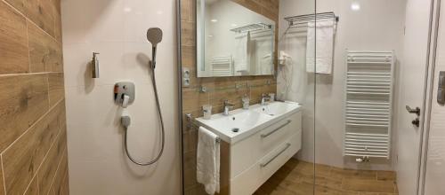 a white bathroom with a sink and a shower at Wellness & Spa Apartments Lipno - Frymburk in Frymburk