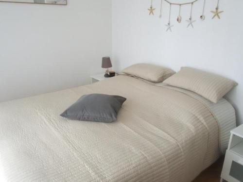 - un lit blanc avec un oreiller gris dans l'établissement Appartement Moderne à Capbreton Près des Plages avec Terrasse et Parking - FR-1-239-455, à Capbreton