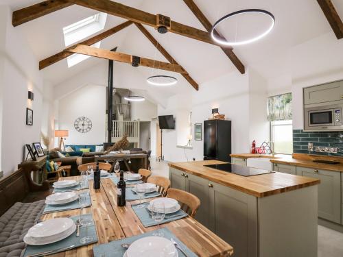 Ysgoldy Brynwyre في Llanrhystyd: مطبخ وغرفة معيشة مع طاولة خشبية طويلة
