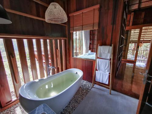 a bathroom with a tub in a room with windows at Pan's farm แบ่งปันฟาร์ม in Ban San Phaya Loei Luang