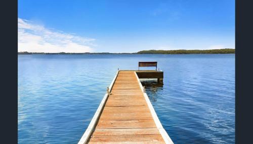 a wooden dock with a bench sitting on top of a lake at Kabine Waterfront Lakehouse in Sunshine in Summerland Point