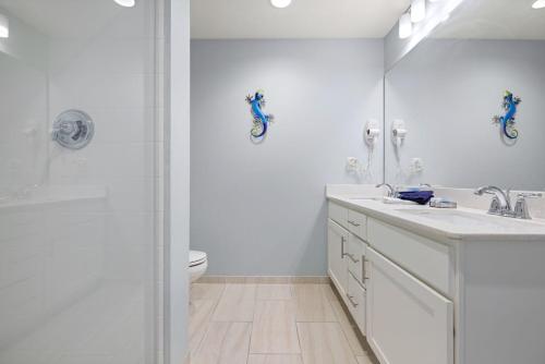 a bathroom with a sink and a toilet and a mirror at Brand New Calypso Resort Tower 3! Sleeps 9! Free Beach Chair Service! by Dolce Vita Getaways PCB in Panama City Beach