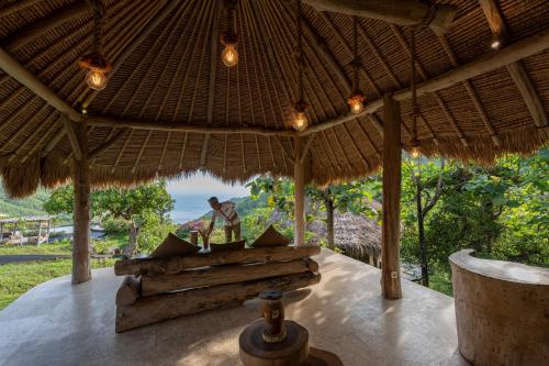 a pavilion with a table under a straw umbrella at MATHIS Lodge Amed in Amed
