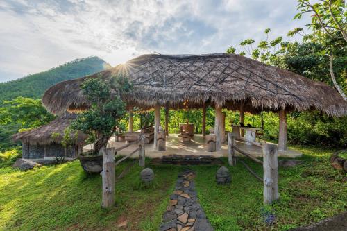 a hut with a grass roof and a pathway at MATHIS Lodge Amed in Amed