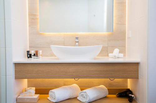 ein Badezimmer mit einem Waschbecken und Handtüchern auf einem Regal in der Unterkunft The Esplanade Motel in Batemans Bay