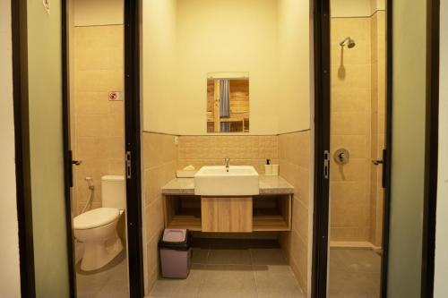 a bathroom with a sink and a toilet and a mirror at K Hostel Seminyak in Seminyak