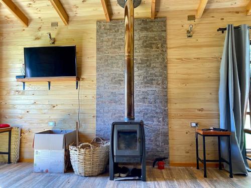 a wood stove in a room with a tv at Cabaña Loncoche, villarrica in Loncoche