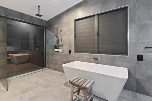 ein Badezimmer mit einer großen weißen Badewanne und einer Dusche in der Unterkunft Villa Thirty One - Balinese inspired Escape in Cairns