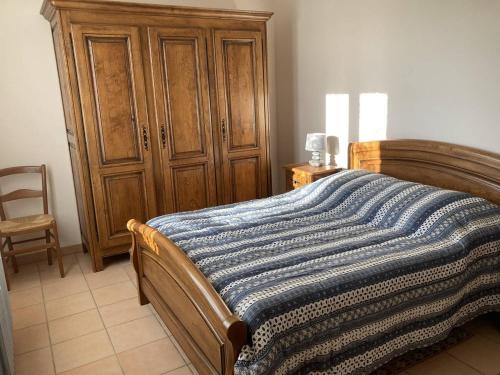 a bedroom with a bed and a wooden cabinet at Maison Ruoms, 3 pièces, 4 personnes - FR-1-697-2 in Ruoms