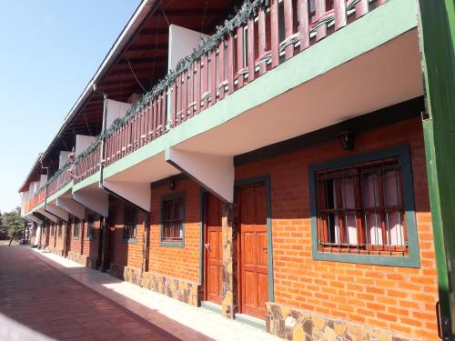 a brick building with brown doors and a balcony at Madre Selva Iguazu in Puerto Iguazú