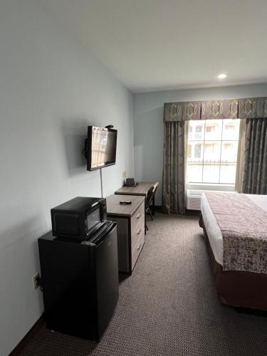 a hotel room with a bed and a desk with a television at Americas Best Value Inn Sulphur in Sulphur
