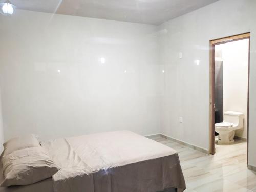 a white bedroom with a bed and a toilet at Hotel Blue Turtle in Bacalar