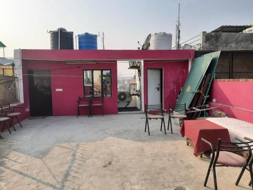 un bâtiment rose avec des chaises et des tables sur une terrasse dans l'établissement Thomas Home Stay, à Agra