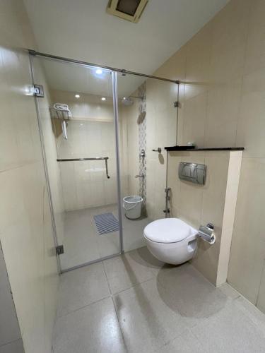 a bathroom with a toilet and a glass shower stall at Anukulas Residency - Vellore in Vellore