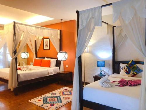 a bedroom with two beds with orange walls at Vdara Pool Resort Spa Chiang Mai in Chiang Mai