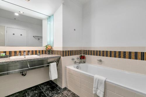 een badkamer met een bad, een wastafel en een spiegel bij Central Corporate Character in Auckland