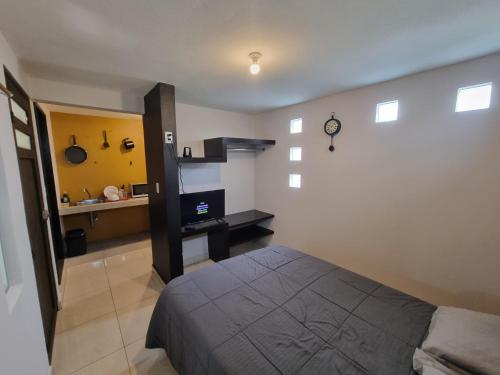 a bedroom with a bed and a kitchen in the background at Departamentos fresno! Una excelente opción in Toluca