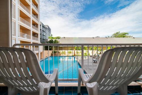 two chairs on a balcony with a swimming pool at Best Bella Pattaya in Pattaya North