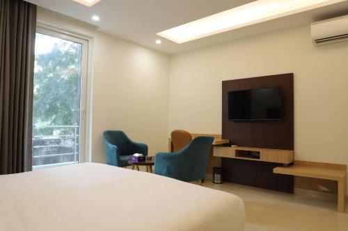 グルガオンにあるHotel Gurugramのベッドとテレビが備わるホテルルームです。
