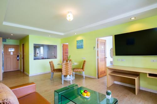 a living room with a television and a table with chairs at Best Bella Pattaya in Pattaya North