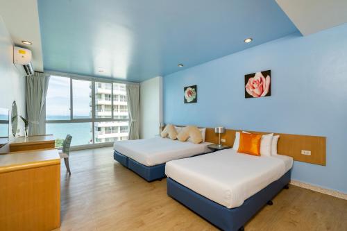 a hotel room with two beds and a desk at Best Bella Pattaya in Pattaya North