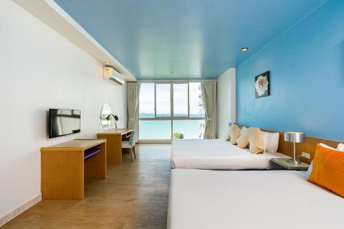 a hotel room with two beds and a television at Best Bella Pattaya in Pattaya North