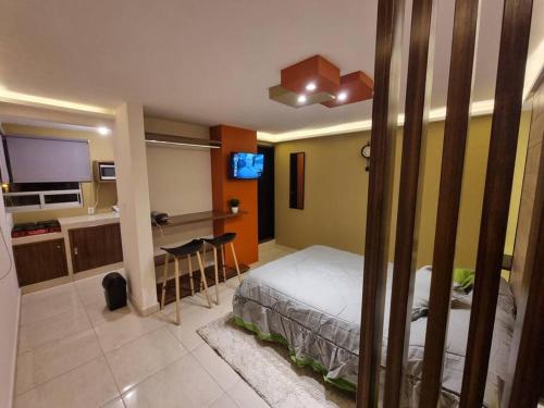 a bedroom with a bed and a desk and a kitchen at Departamentos fresno! Tu mejor opción in Toluca