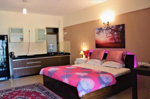 um quarto com uma cama com um edredão rosa em Portofino em Lavasa