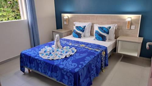 Habitación de hotel con cama con colcha azul en Résidence Paradis, en Petit-Bourg
