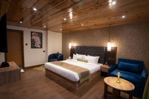 a hotel room with a bed and two blue chairs at Mount Magnolia Boutique Hotel & Spa in Pelling