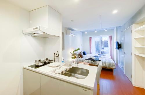a white kitchen with a sink and a bed at japan house nishishinjuku in Tokyo