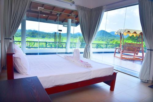 a bedroom with a bed with a view of a balcony at MARGOSA MOUNTAIN VILLA in Galewela