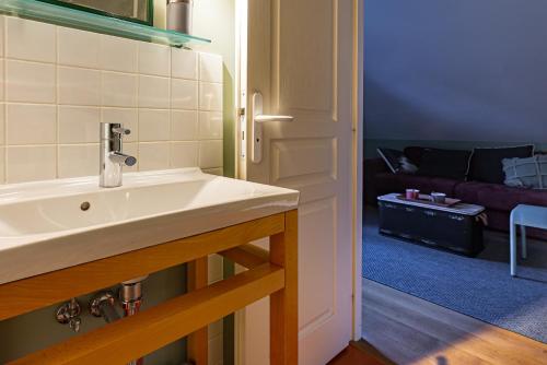 a bathroom with a sink and a living room at L'étape des Marcs d'Or in Dijon