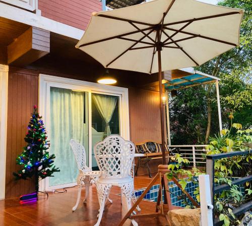 um alpendre com uma mesa, um guarda-chuva e uma árvore de Natal em lemoon house khaoyai em Khao Yai