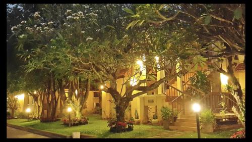 a building with a tree in the yard at night at Areena Resort and Hotel Uttaradit in Uttaradit