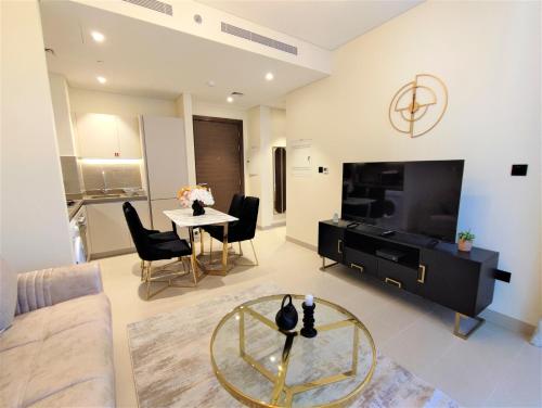 a living room with a couch and a tv and a table at Modern 1 bedroom - Close to Business Bay - Sobha Creek Vista in Dubai