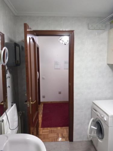 a bathroom with a toilet and a door with a red rug at Apartamento Los Fresnos in Gijón