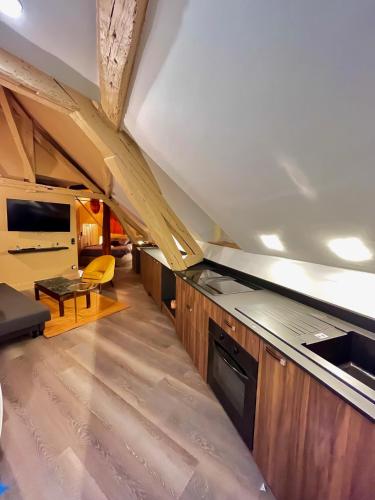 une cuisine mansardée avec des placards en bois et une table dans l'établissement Romain - Appartement à Reims, à Reims