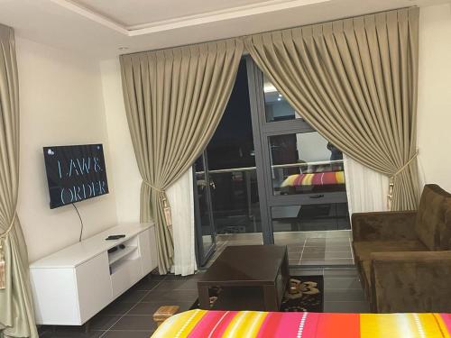 a room with a bed and a couch and a window at Park D-plus Apartments Cantonments in Accra