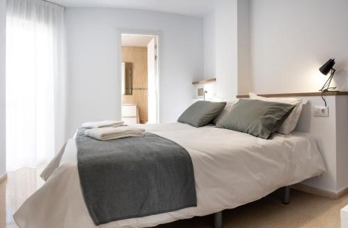 1 dormitorio con 1 cama blanca grande con almohadas grises en CALMA Apartments, en Benidorm